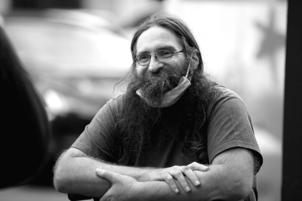 Aufnahme eines Obdachlosen mit Bart und Kappe in Hamburg, der seitlich fotografiert wurde, Schwarz-Weiß-Porträt.