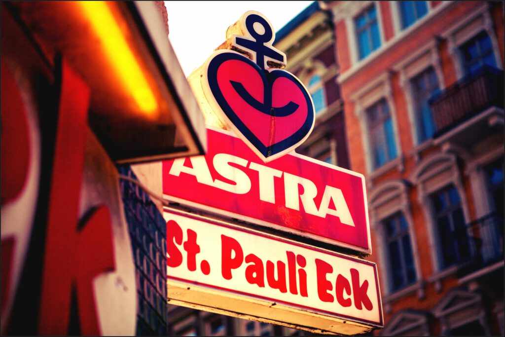 Leuchtschild Astra St. Pauli Eck in Hamburgs Kultviertel mit Altbau-Fassade im Hintergrund.