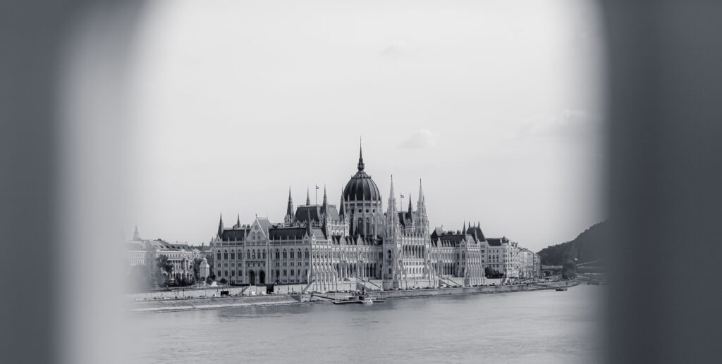 Schwarz-weiß Fotografie des Parlaments in Budapest, aufgenommen von der Donauseite mit Blick auf die markante Kuppel.