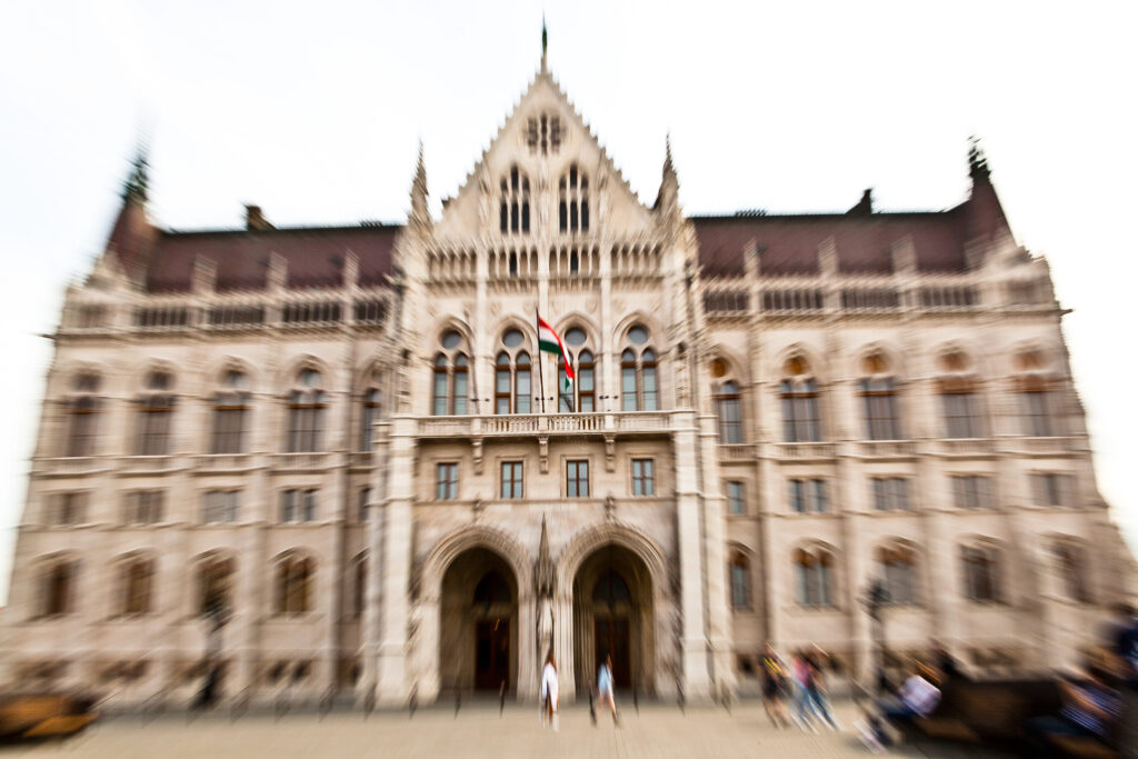 Das ungarische Parlament in Budapest mit wehender Flagge, aufgenommen in Bewegungsunschärfe.