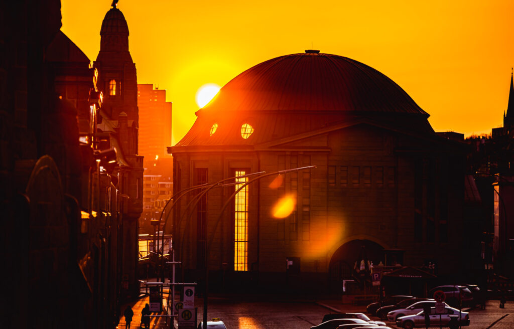 Sonnenuntergang hinter den Landungsbrücken in Hamburg, das Licht strahlt durch die Fenster des Alten Elbtunnels.