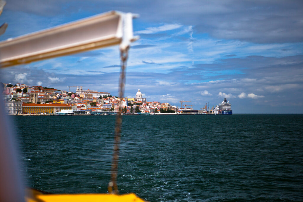 Blick vom Wasser auf Lissabon mit bunten Häusern, dem Panteão Nacional und Kreuzfahrtschiff im Hafen.