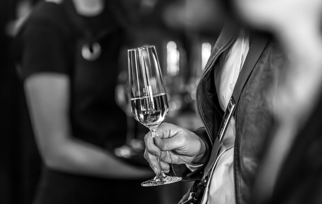 Hand hält ein Glas Sekt bei einem Event.