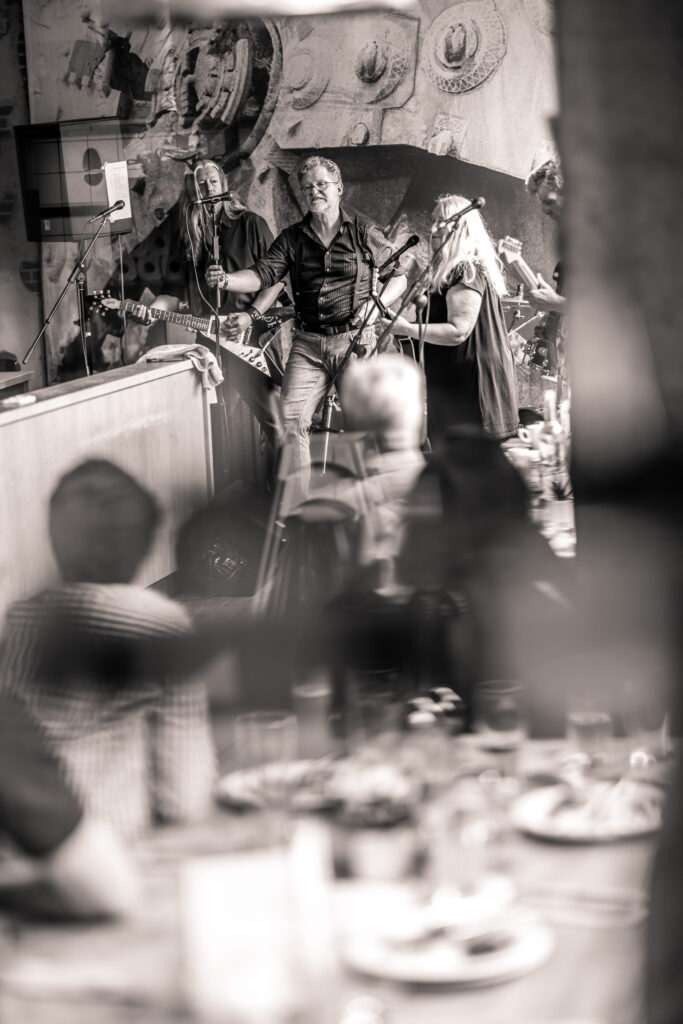 Schwarz-weiß-Aufnahme einer Band, die live in der Trude Hamburg vor Publikum auftritt.