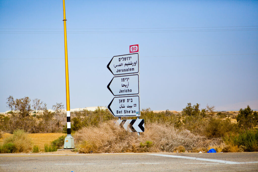 Straßenschild im Jordantal mit Wegweisern nach Jerusalem, Jericho und Bet She’an auf Hebräisch, Arabisch und Englisch.