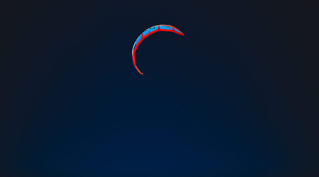 Bunter Kite-Segel vor tiefblauem Himmel an der Atlantikküste Portugals.